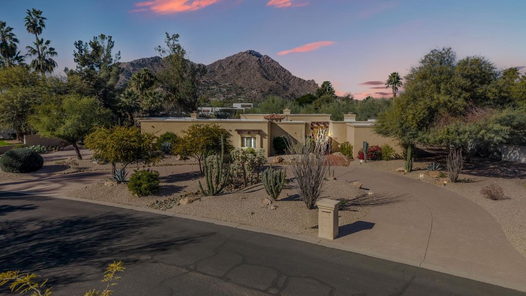 Desert-landscaped Santa Fe style home at dusk with Camelback Mountain behind