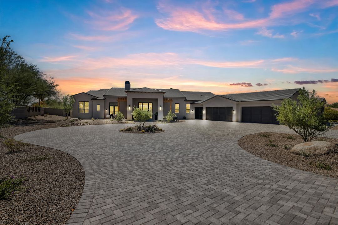 New-build home at sunset behind a sweeping paver drive