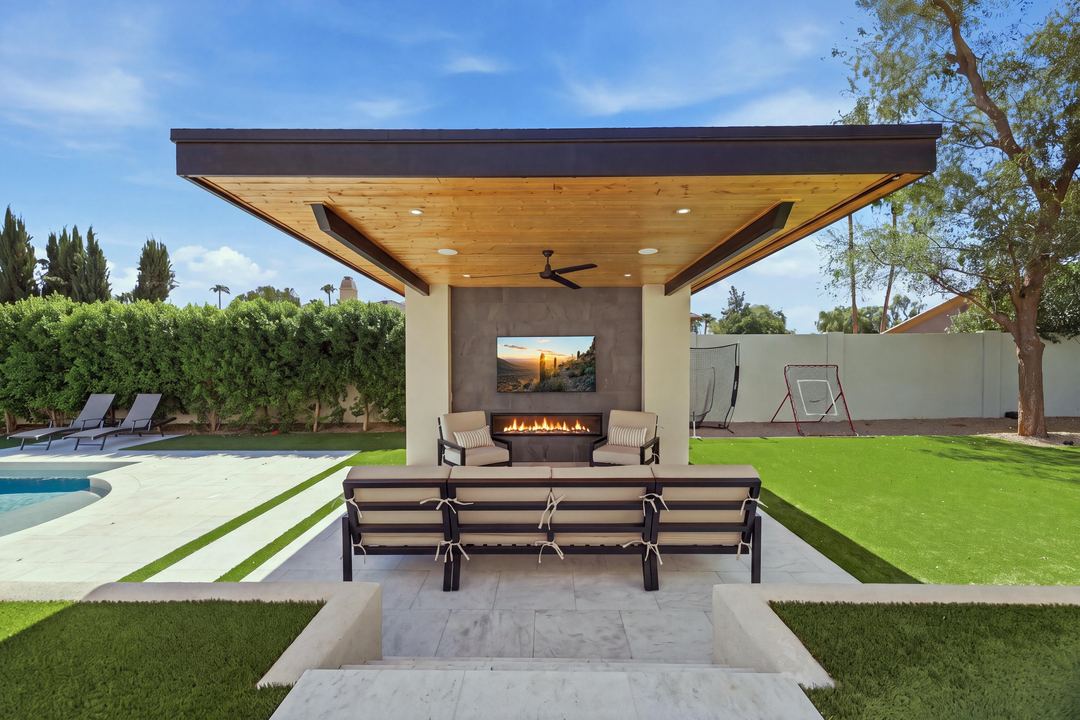 Poolside cabana with a wood ceiling, a fireplace and lounge seating on the lawn