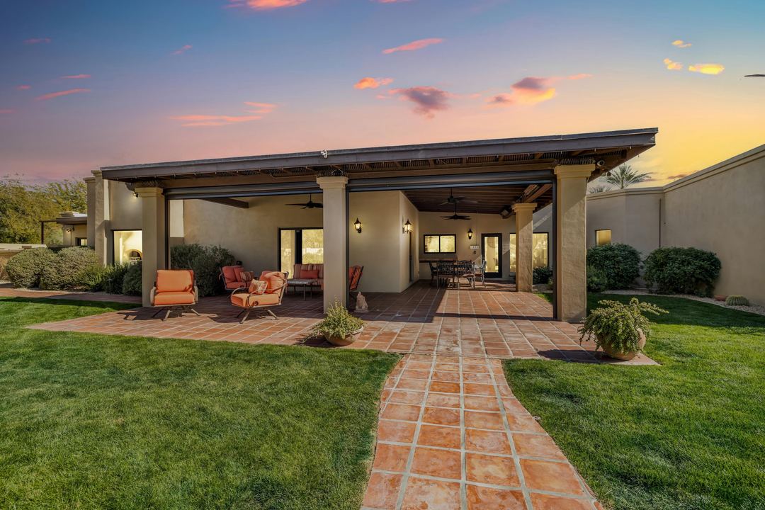 Covered patio at sunset with a tile path across the lawn