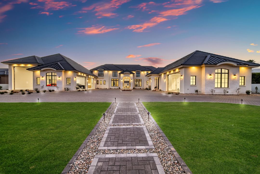 Paver walk across the lawn to the lit estate at sunset