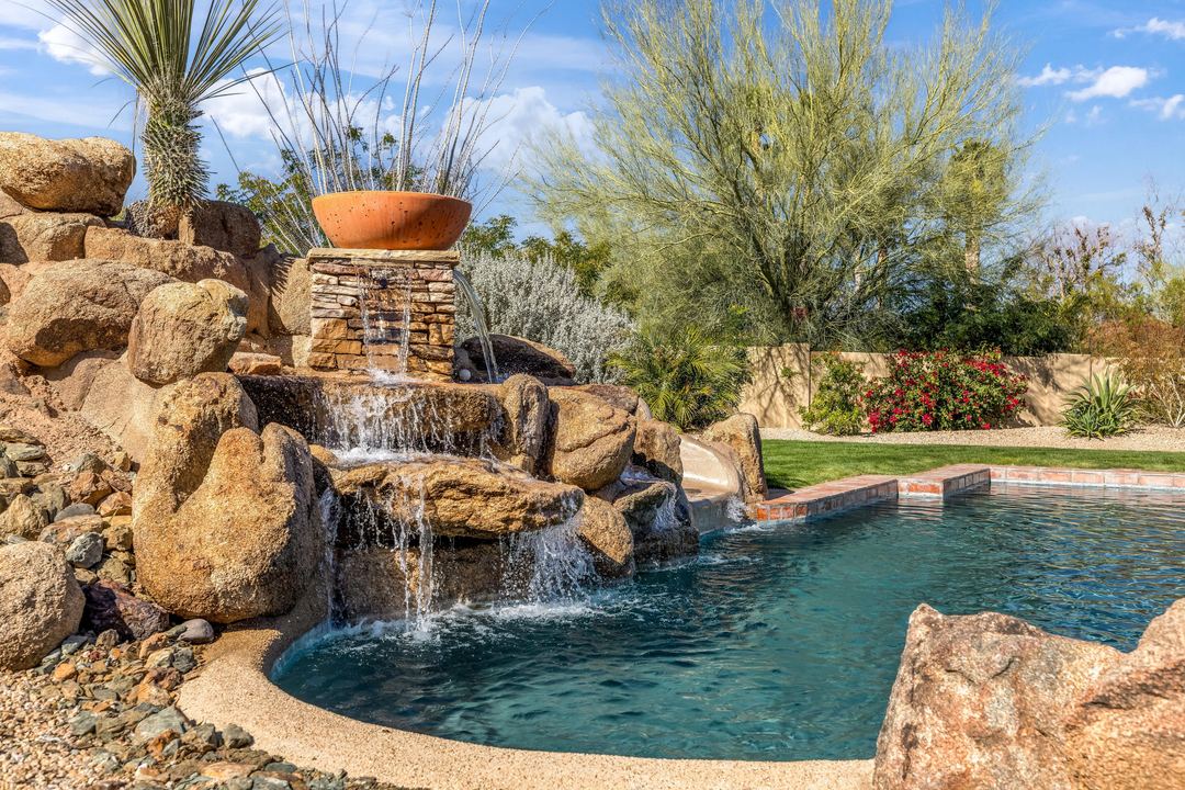 Rock waterfall spilling into a free-form pool among desert plantings