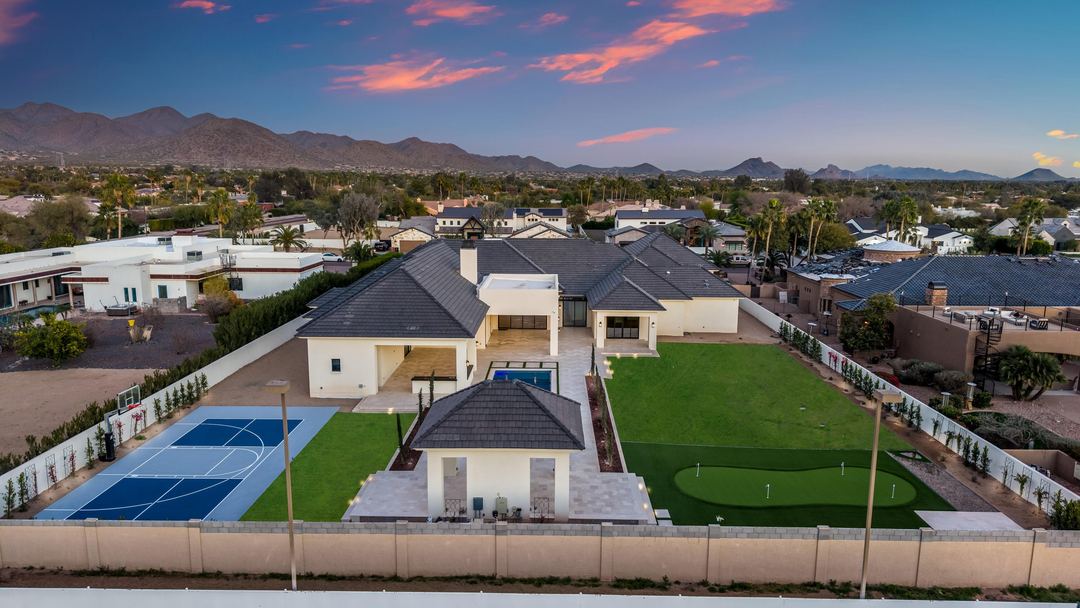 Twilight aerial of the backyard: a sport court, a putting green and the pool cabana