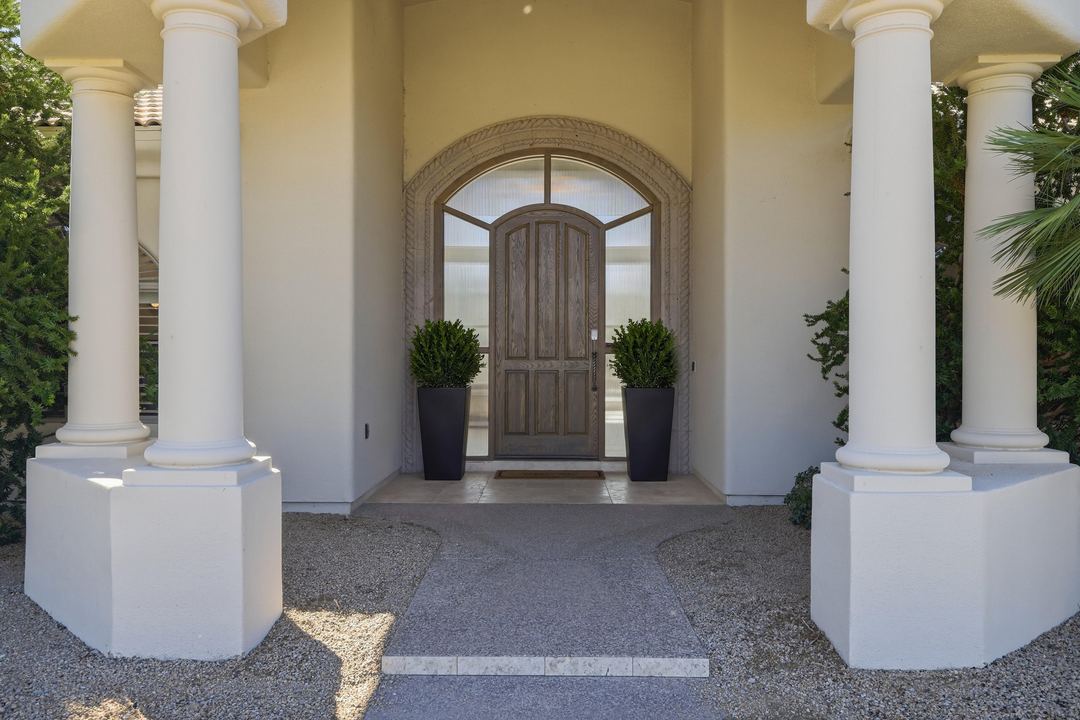 Columned entry with an arched wood door in daylight
