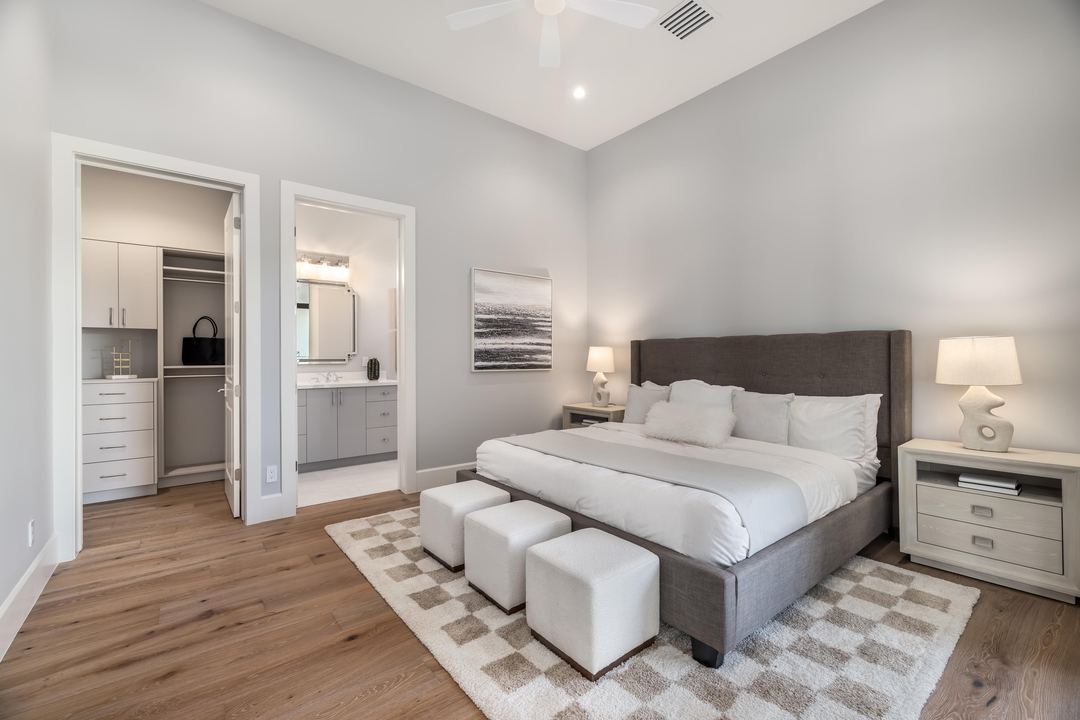 Bedroom suite with a padded headboard, a checked rug and a walk-in closet
