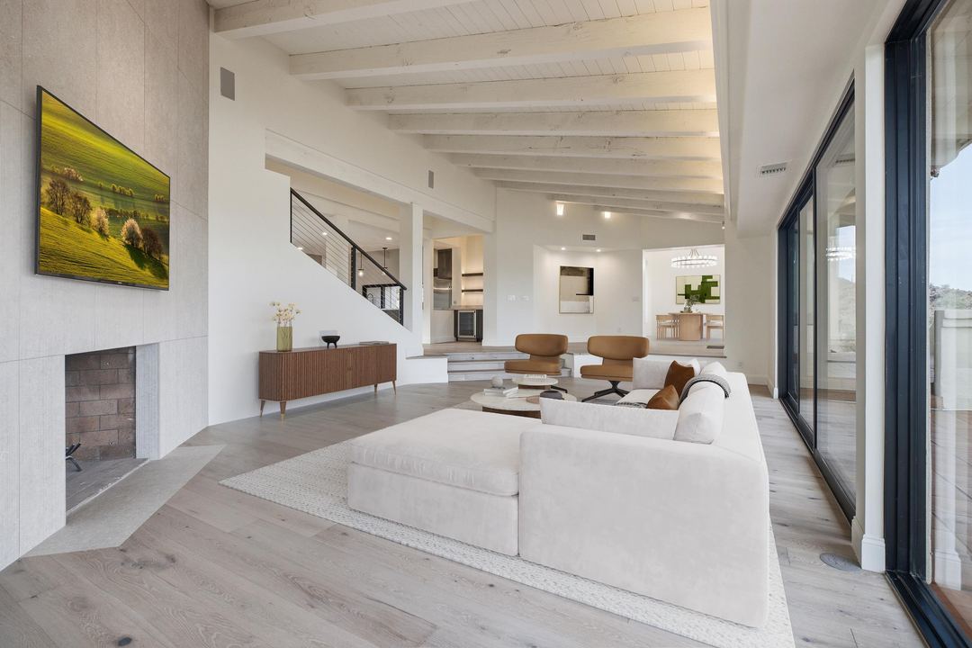 Great room with a white sectional, a fireplace and a wall of sliding glass, virtually staged