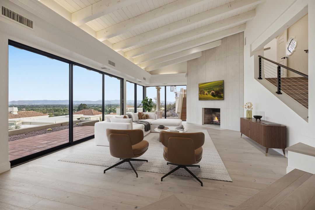 Living room with leather lounge chairs and floor-to-ceiling glass looking over the city, virtually staged