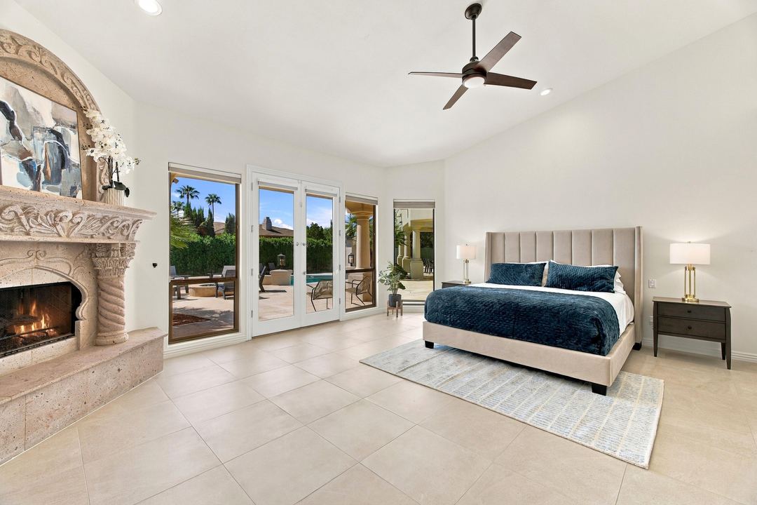 Primary suite with a carved stone fireplace and French doors to the patio