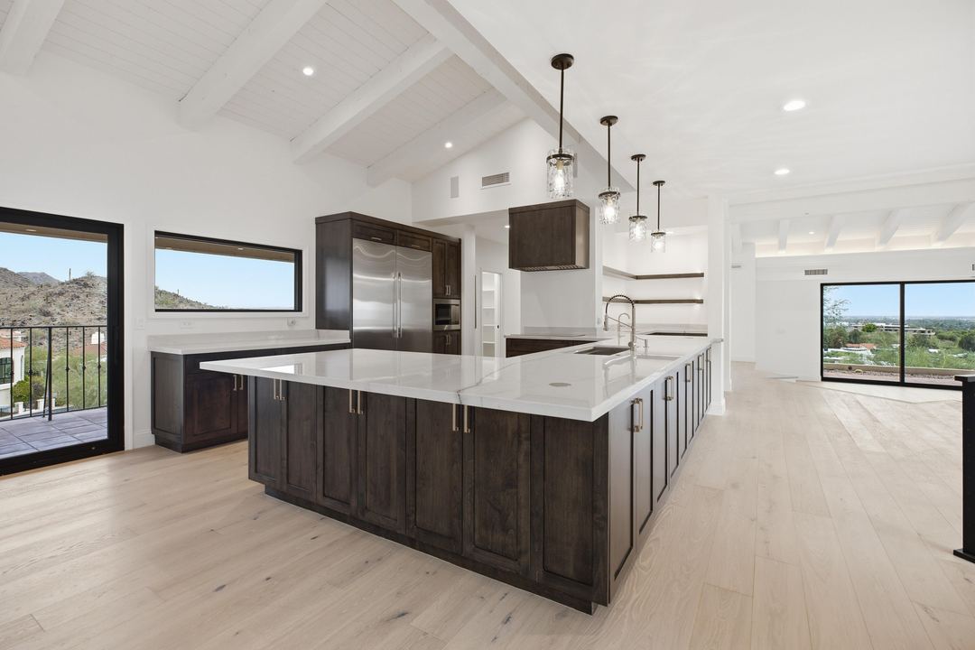 Kitchen with a long dark-wood island, white quartz and pendant lights under a vaulted ceiling