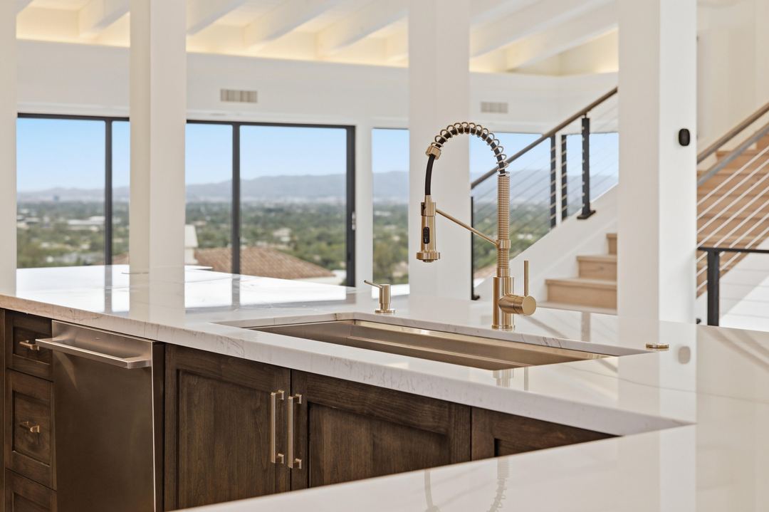 Brass faucet at a quartz island, with the city skyline through the windows behind