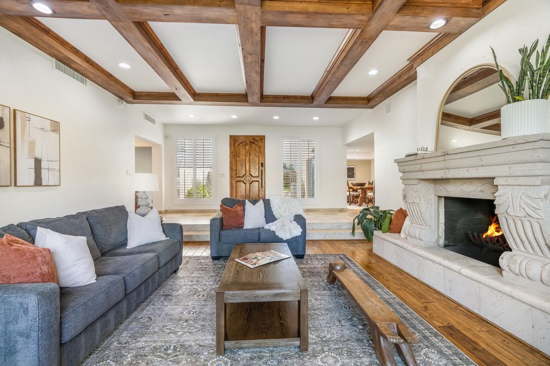 Family room with a carved stone fireplace, a beamed ceiling and hardwood floors