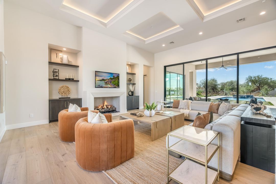 Living room with a fireplace, leather swivel chairs and a glass wall to the yard