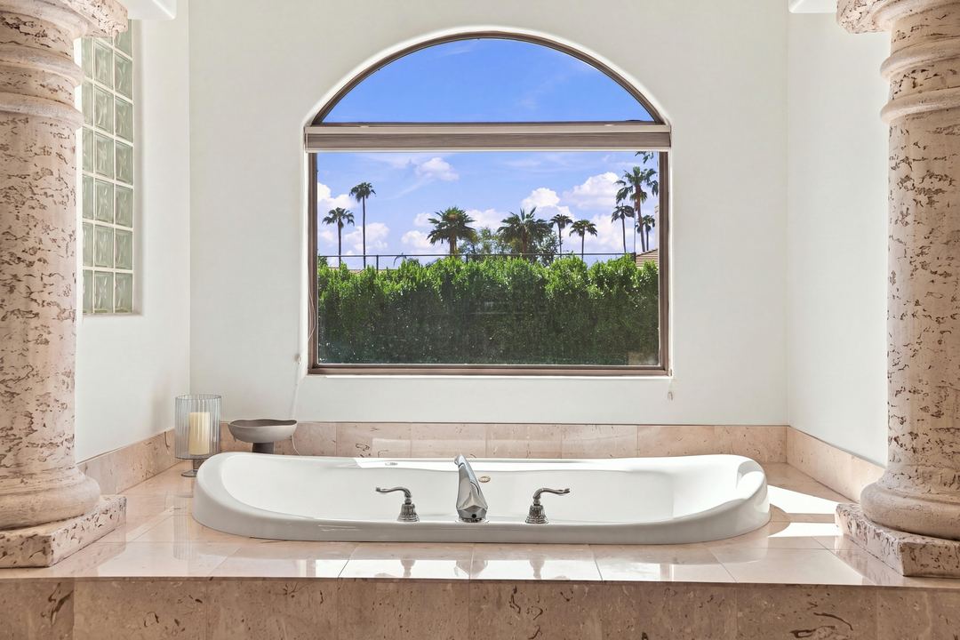 Soaking tub framed by stone columns under an arched window