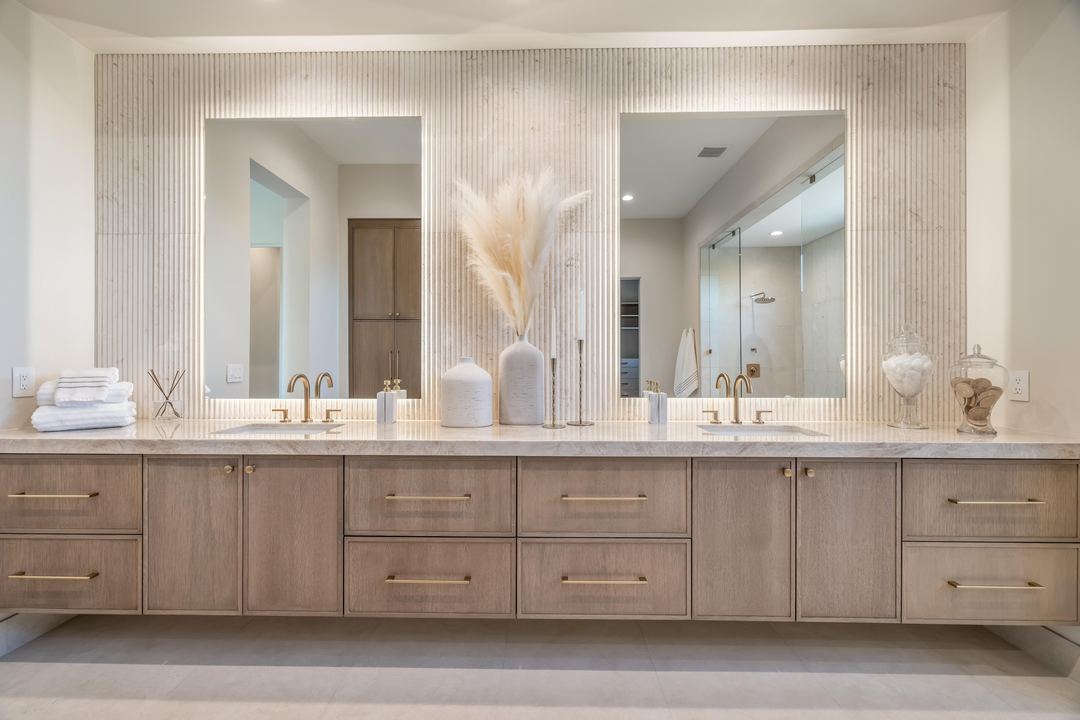 Double vanity in warm wood with a fluted stone wall
