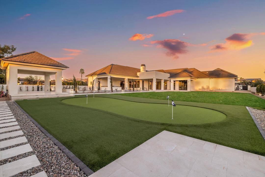 Backyard putting green at sunset with the estate behind