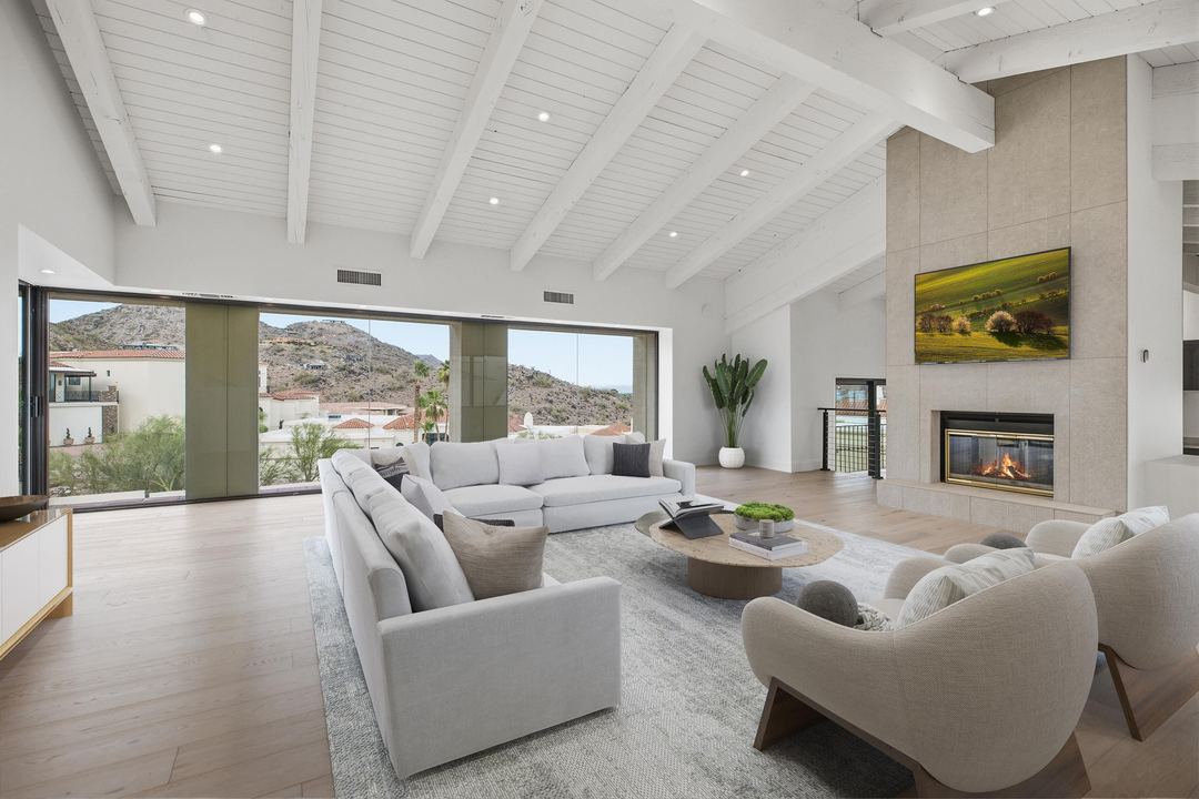 Vaulted family room with white beams, a fireplace and sliding glass to the hillside, virtually staged