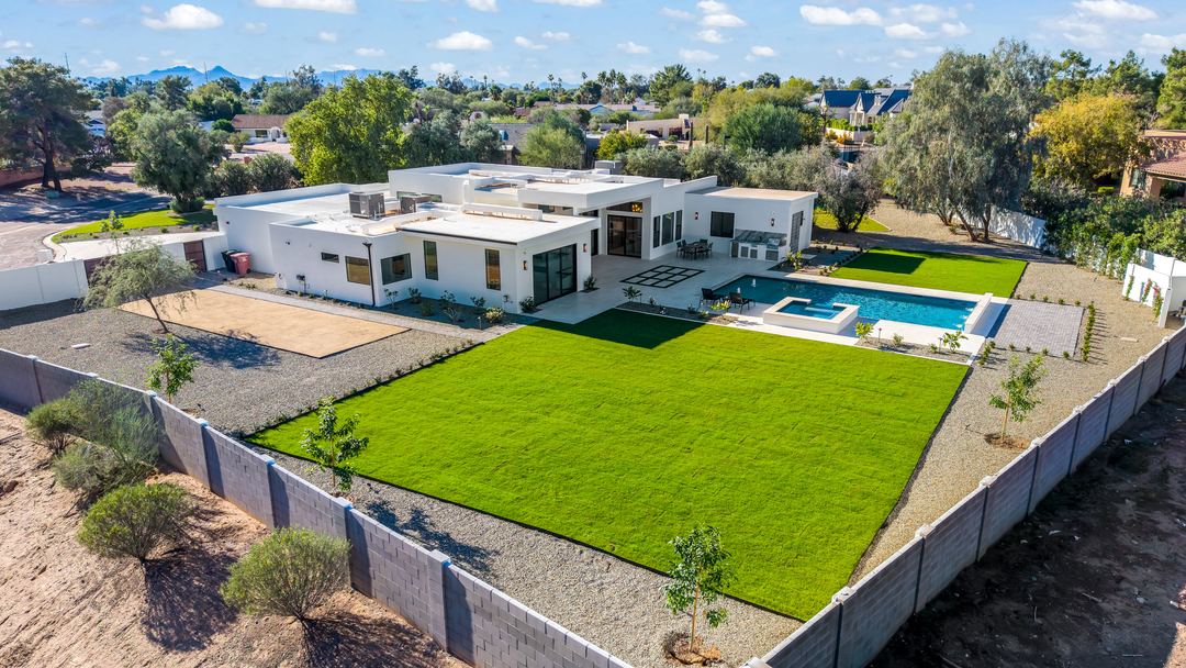 Daytime aerial of a modern estate with a lawn and pool
