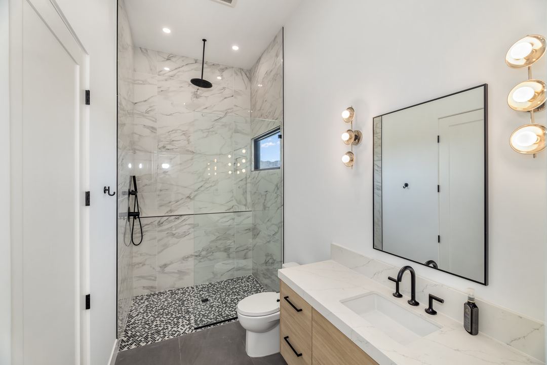 Bathroom with a marble shower, an oak vanity and brass fixtures