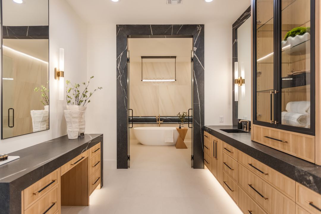 Primary bathroom with a freestanding tub, black marble and oak cabinets