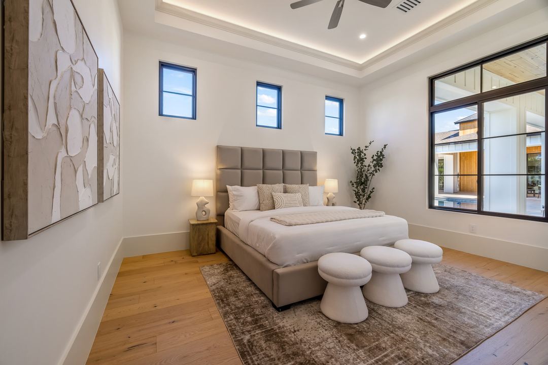 Bedroom with a tall upholstered headboard and a window onto the patio