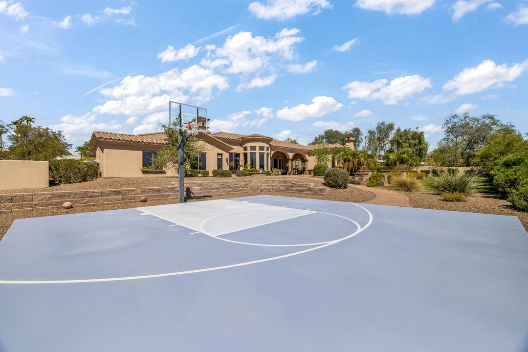 Backyard sport court with the home and desert beyond
