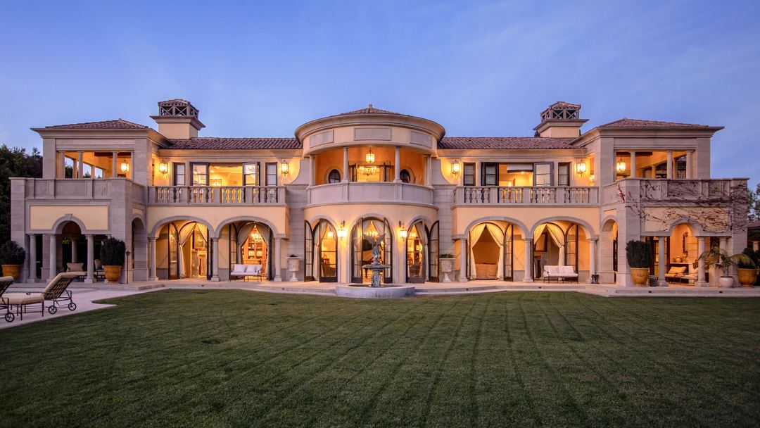 Mediterranean estate at dusk with a lawn and pool in front