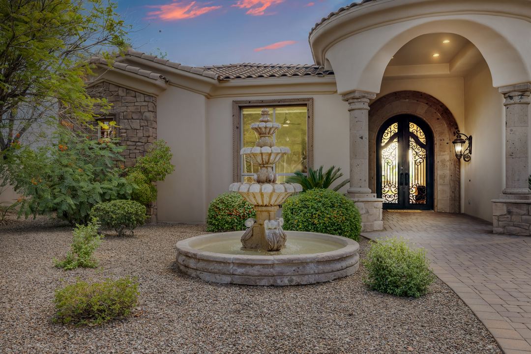 Stone fountain in front of an arched iron entry door