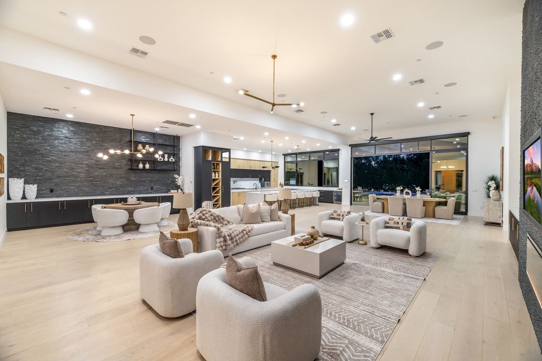 Great room with white boucle seating, a stacked-stone wall and the kitchen beyond
