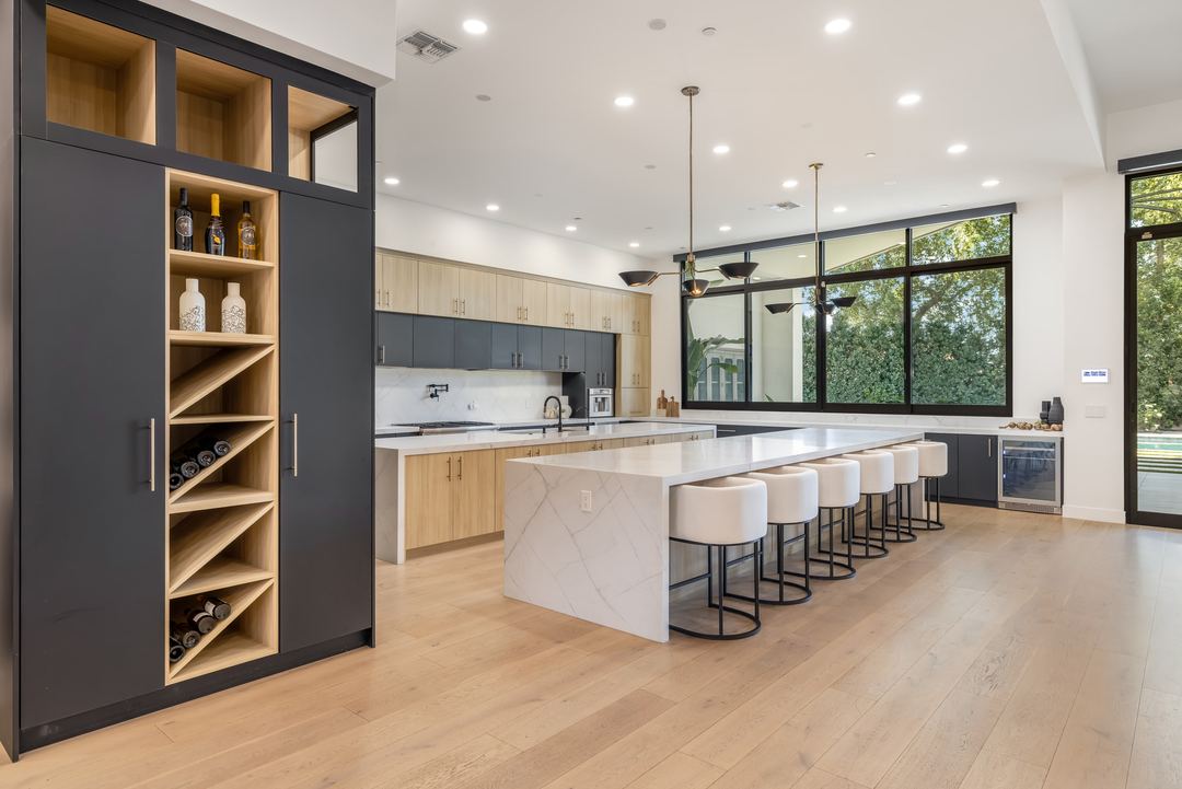 Kitchen with a long marble island, oak cabinets and a wine display