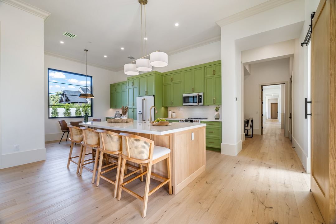 Kitchen with green cabinets, a white island and oak floors