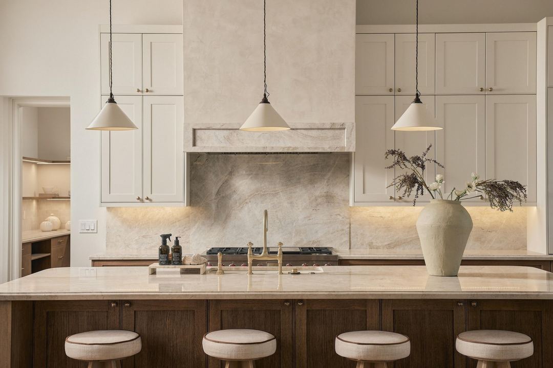 Kitchen straight on, with a stone backsplash, a plaster range hood and glass pendants