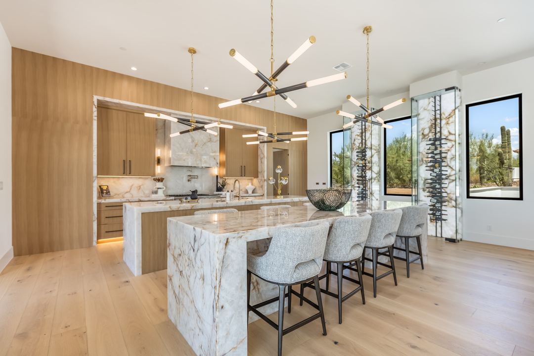 Kitchen with a marble island, oak cabinets and a brass chandelier