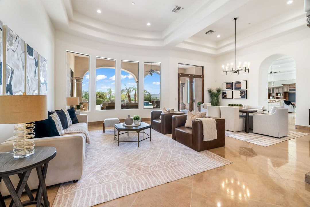 Living room with tall windows, travertine floors and a chandelier