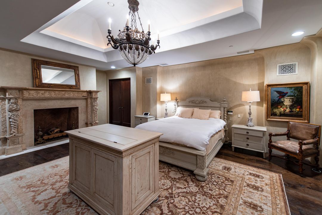 Primary bedroom with a carved fireplace and a chandelier