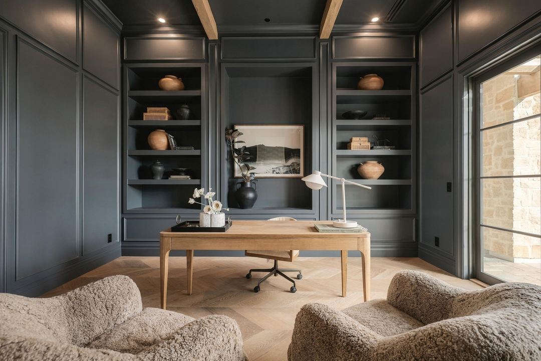 Dark-paneled office with a marble fireplace, built-in shelves and a wood desk