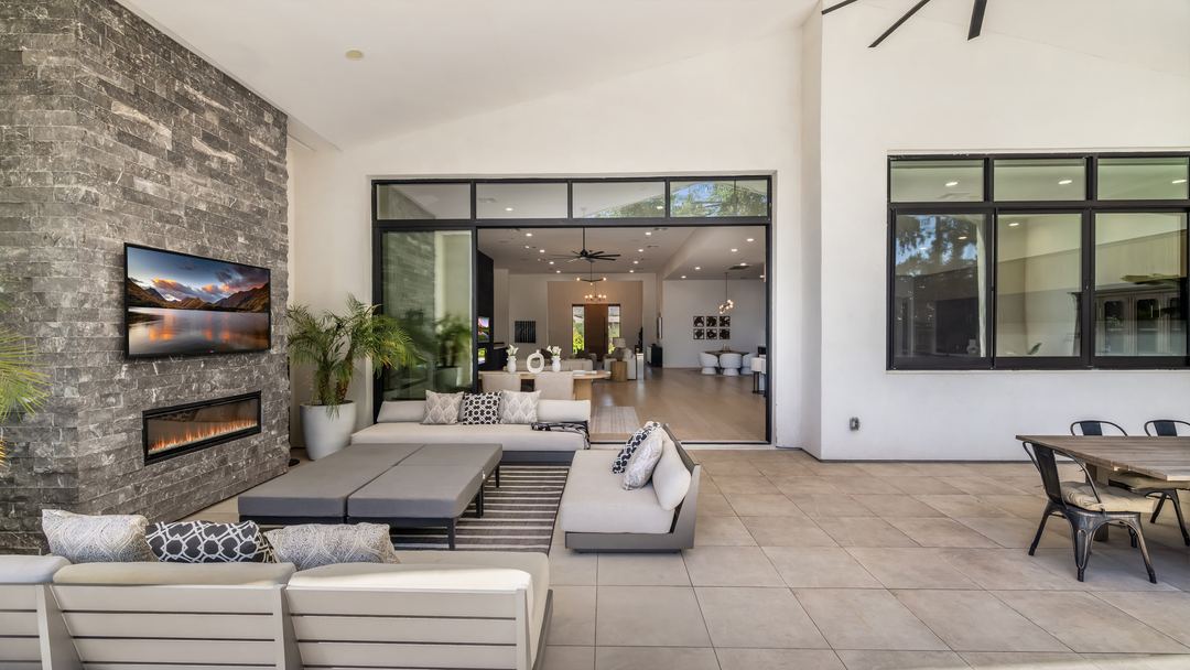 Covered patio with a stone fireplace and lounge seating, open to the pool