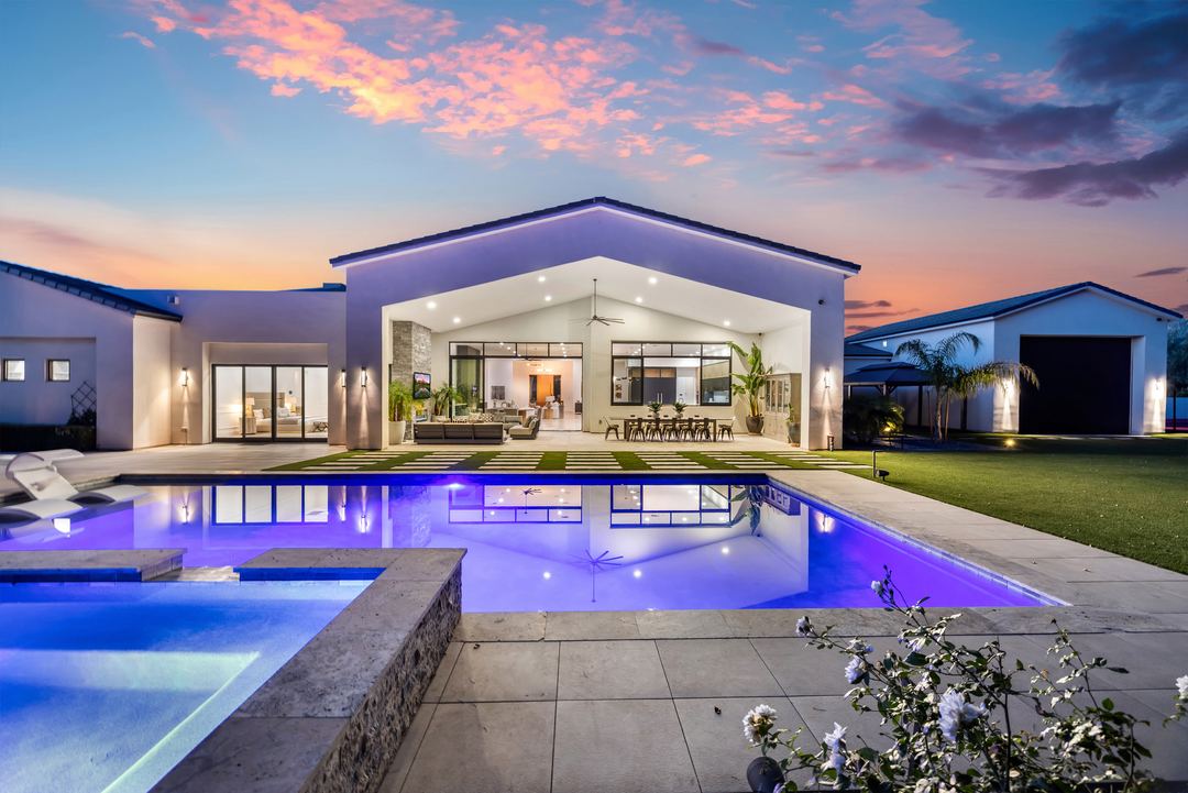 Backyard pool lit purple at twilight, with the great room glowing behind it