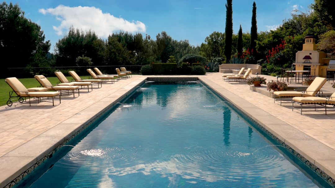 Long pool with loungers and an outdoor kitchen at the far end