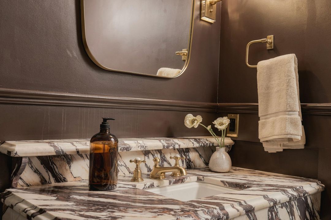 Powder room with plum walls and a veined marble vanity