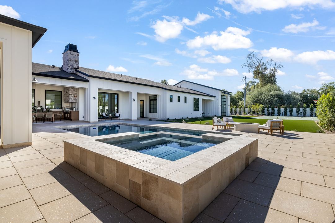 Raised spa and pool with the home and lawn behind