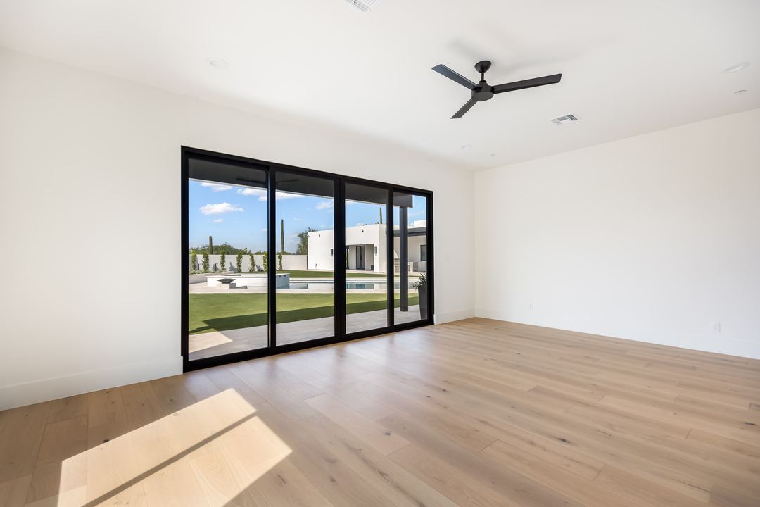 Empty bedroom with oak floors and sliding doors to the backyard
