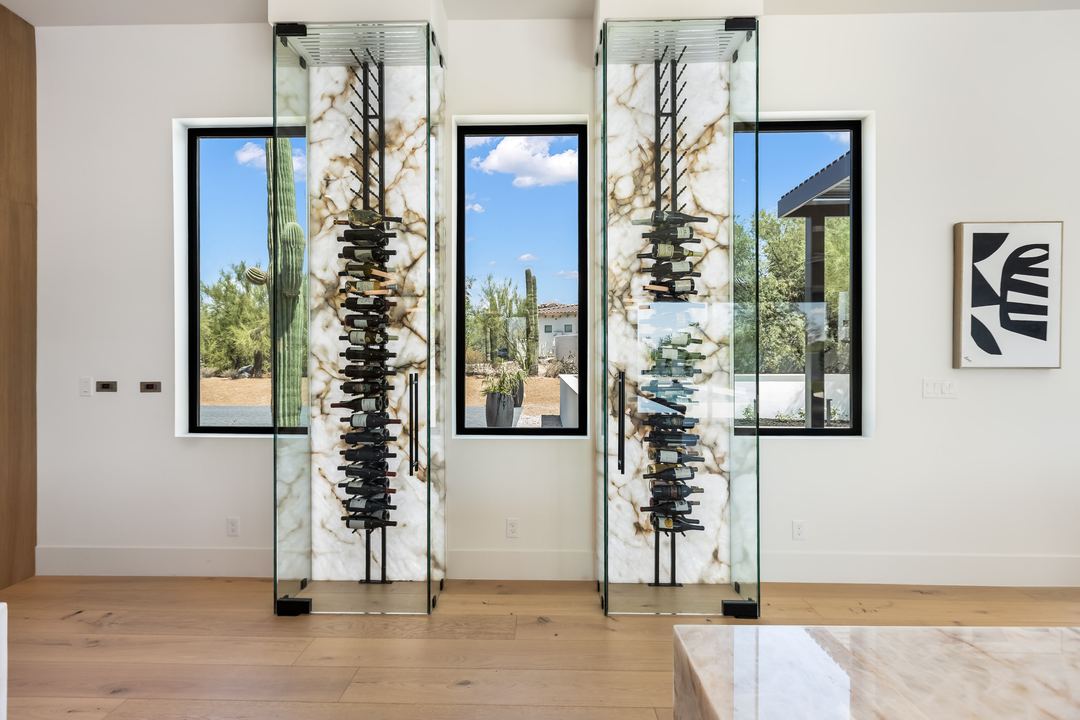Glass wine wall between two black-framed windows