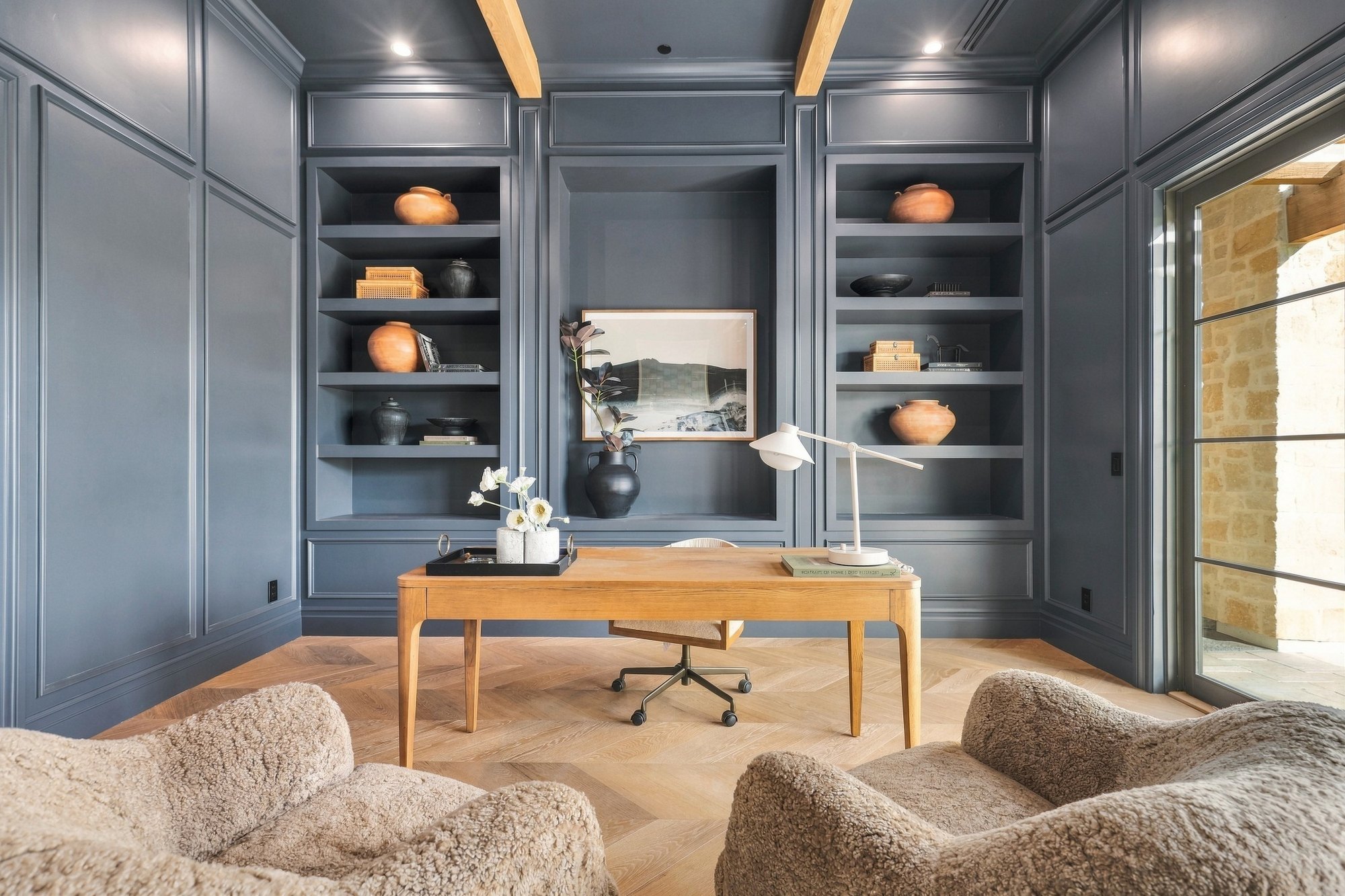 Navy-paneled office with built-in shelves and a wood desk, lit with flash