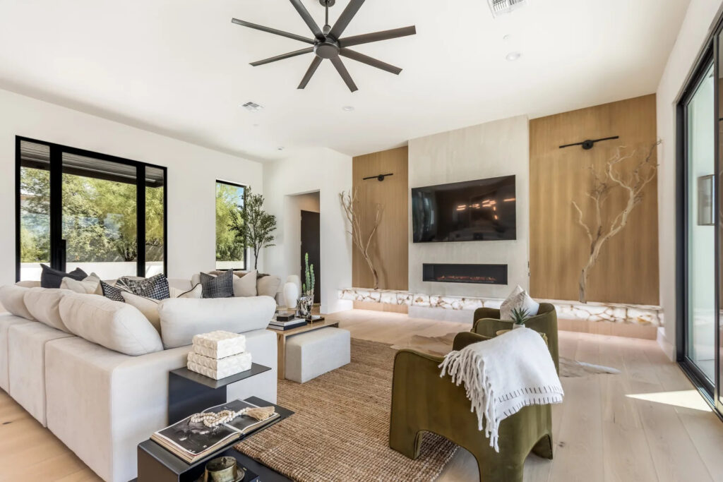 Real estate photography in Scottsdale AZ featuring a modern living room with fireplace, white sectional, and ceiling fan
