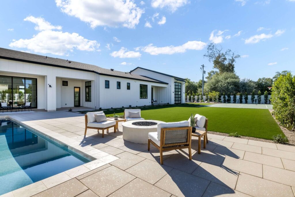 Real Estate Videography Services in Phoenix, AZ 1 Professional real estate photography of a modern Phoenix, AZ home backyard featuring a patio pool, fire pit, and synthetic turf lawn